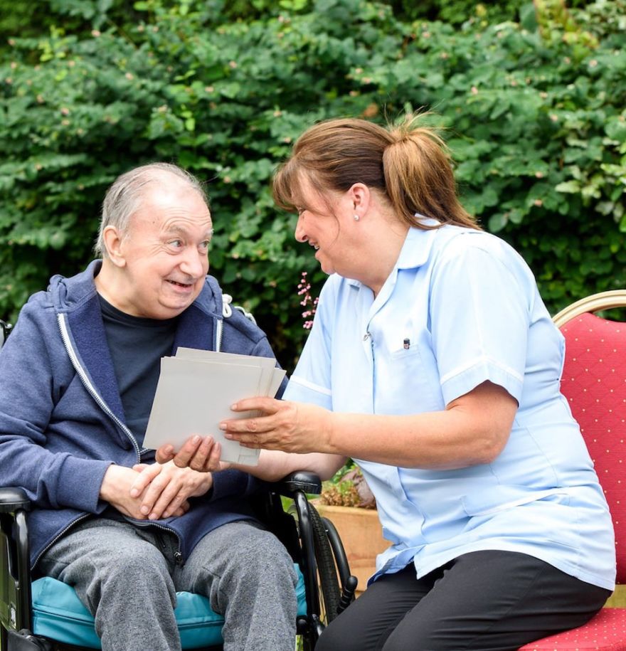 team member looking at cards with male resident in garden