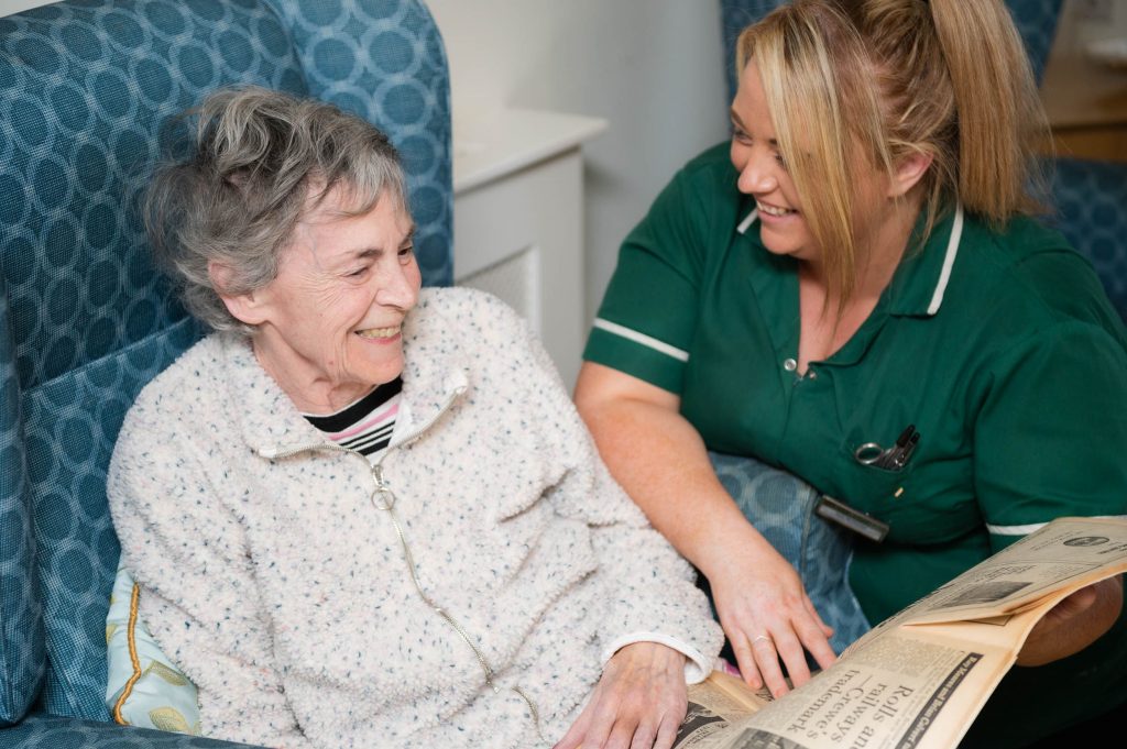 Elderly resident reading , chatting and laughing with a member of staff